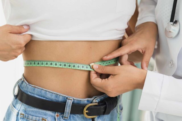 close up doctor measuring womans abdomen