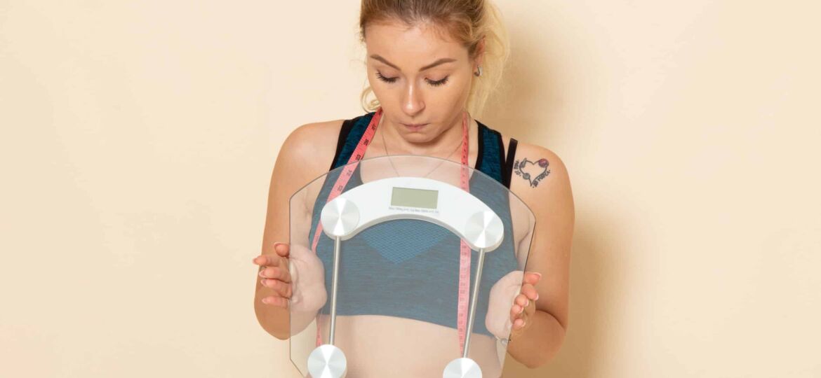 front view young female sport outfit holding scales white wall fit body sport beauty health exercise
