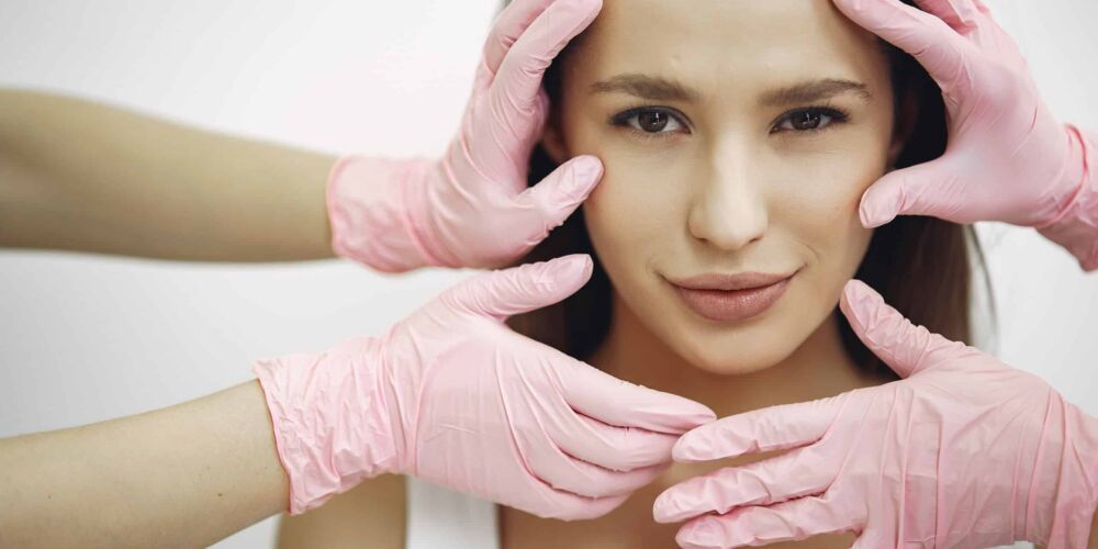 Woman standing in a cosmetology studio Cosmetology theme. Lady in a beauty studio. Hands in gloves near the girl's face.