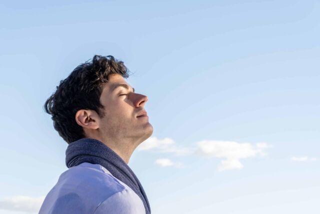 young boy with his head to the sky and eyes closed on a clear day