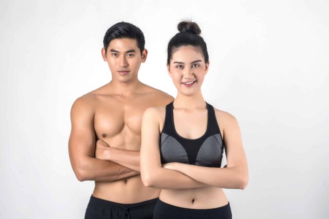 Muscular couple showing six pack abs isolated on white backgroun