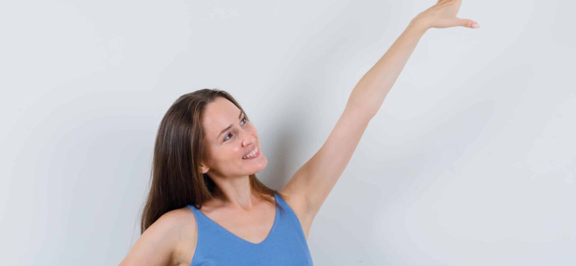 young lady stretching arm in singlet, skirt and looking cheerful , front view.