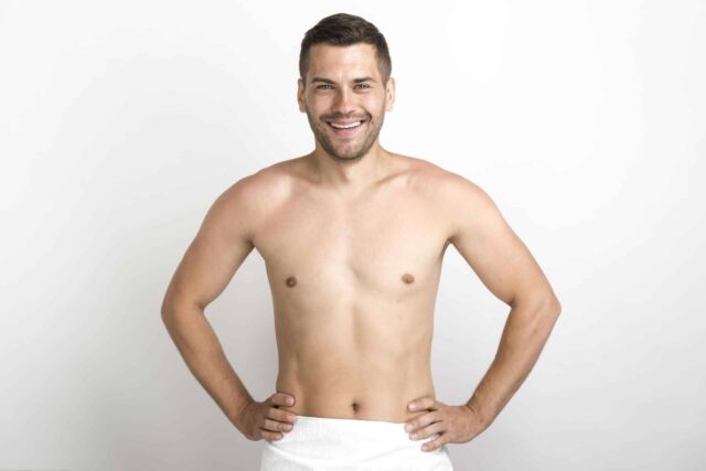 hombre-sin-camisa-feliz-posando-contra-la-pared-blanca