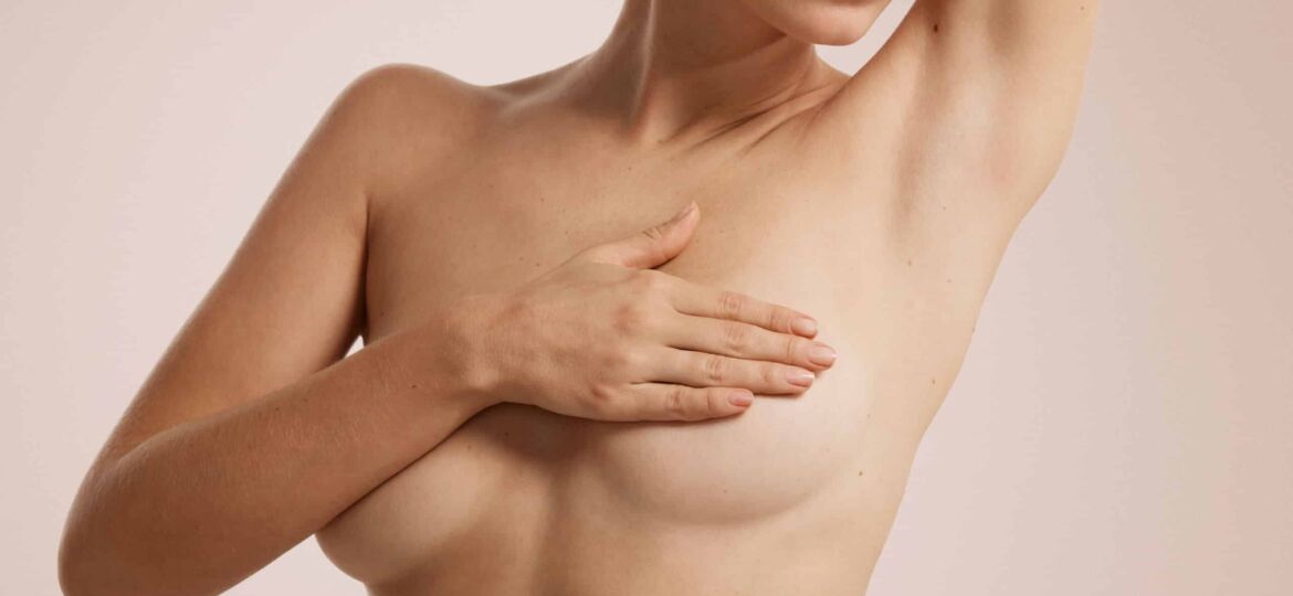 Closeup cropped portrait young woman with breast pain touching chest colored isolated on background