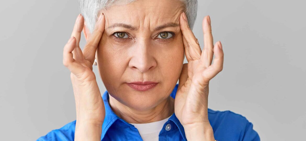 Stylish middle aged Caucasian female in blue shirt suffering fro