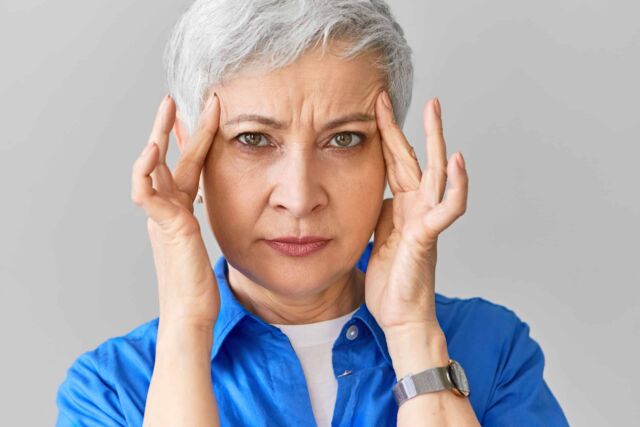 Stylish middle aged Caucasian female in blue shirt suffering fro